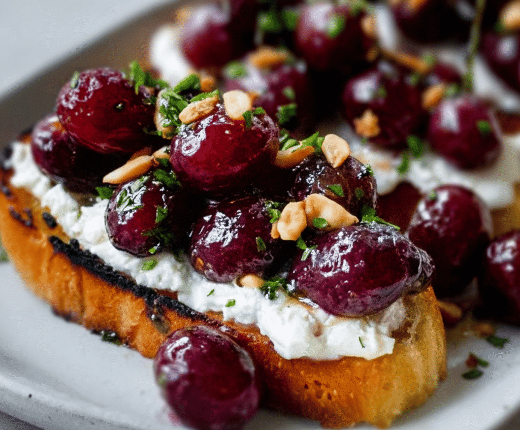 Delicious baked grapes and whipped feta on crispy bruschetta, perfect for a gourmet appetizer.