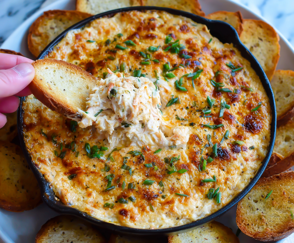 Creamy hot crab dip served in a bowl with crispy crackers, perfect for sharing at parties.